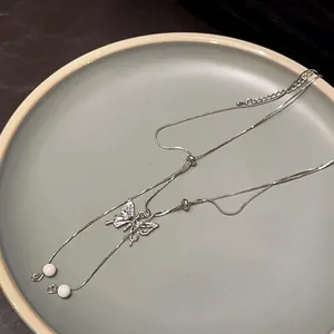 Macro view of silver double-layer necklace featuring crystal butterfly pendant and pearl tassels