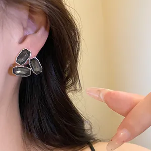 Close-up detail of elegant black crystal cluster stud earrings worn on a model ear.