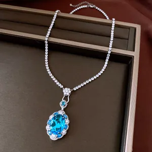Close-up of elegant oval blue zircon pendant necklace with sparkling tennis chain