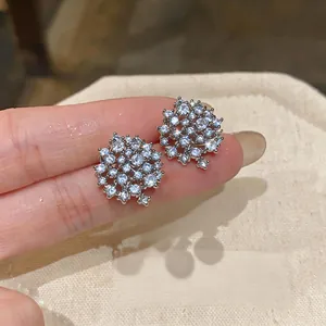 Primo piano di scintillanti orecchini a lobo rotondi in argento con zirconi pavé