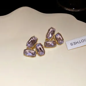 Detailed macro view of elegant lavender octagonal crystal stud earrings on cream tray.