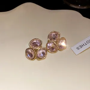 Macro view of elegant pink faceted crystal cluster stud earrings in a gold finish.
