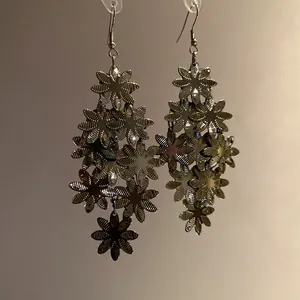 Dettaglio dei ciondoli a fiore in metallo di questi eleganti orecchini pendenti.