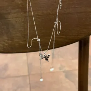 Detailed view of silver butterfly necklace with rhinestones and hanging pearl tassels