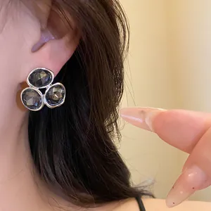 Close-up detail of silver earrings with three faceted dark grey stones on model ear