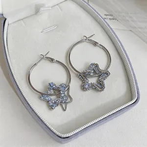 Élégantes créoles argentées avec pendentifs étoiles en résine bleue dans un écrin