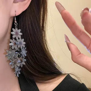 Primo piano di eleganti orecchini a nappa con fiori in metallo indossati per un look chic.