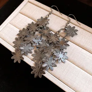 Primo piano di orecchini pendenti a fiori in metallo con trame dettagliate dei petali.
