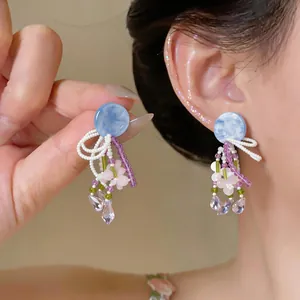 Vue macro détaillée de boucles d'oreilles en perles avec clous runden bleus et fleurs roses