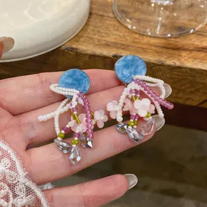 Gros plan de boucles d'oreilles en perles avec fleurs roses et clous ronds bleus.