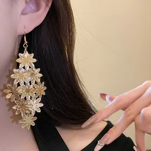 Vista dettagliata di eleganti orecchini pendenti a fiori dorati indossati da una modella
