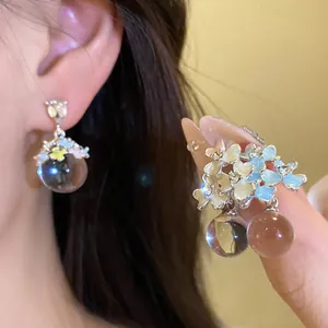 Détail de boucles d'oreilles fleuries style forêt avec fleurs colorées en émail et perles