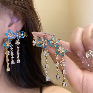 Close-up of elegant flower and star tassel earrings with blue and clear stones