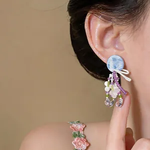 Gros plan de boucles d'oreilles fleuries avec clou marbré bleu et perles violettes