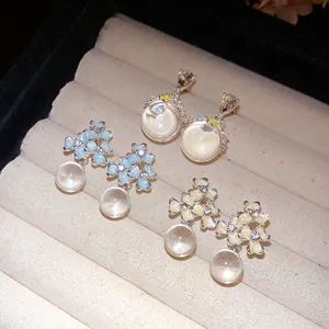 Vue détaillée de boucles d'oreilles en émail floral avec des perles de verre.