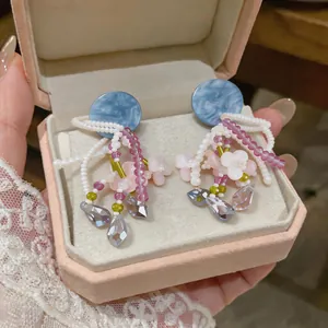 Détail macro de boucles d'oreilles fleuries en perles avec clous bleus et cristaux