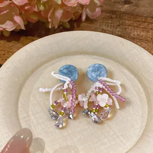 Gros plan de boucles d'oreilles en perles avec clous en marbre bleu et fleurs