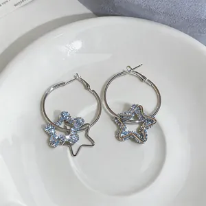 Gros plan de boucles d'oreilles créoles avec des pendentifs étoiles bleus et évidés