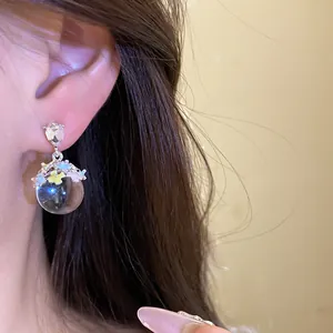 Vue détaillée de boucles d'oreilles d'été avec fleurs en émail coloré et perle