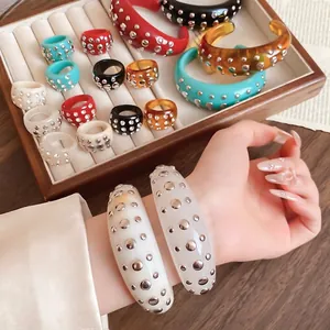 Fashionable resin open bangle with metal rivets shown on wrist and display tray