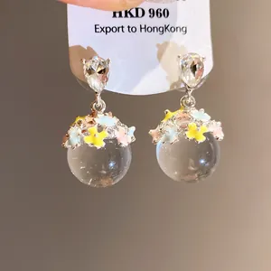 Gros plan de boucles d'oreilles style forêt avec sphères et fleurs colorées