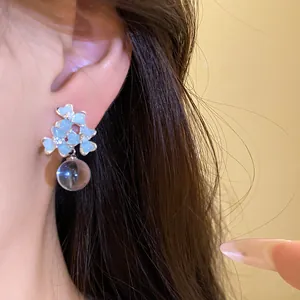 Boucles d'oreilles fleurs bleues éthérées avec goutte transparente, vue détaillée sur l'oreille