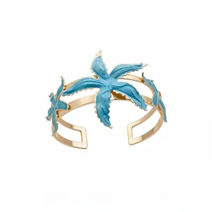 Elegant gold-plated open cuff bracelet featuring vibrant blue enamel starfish charms