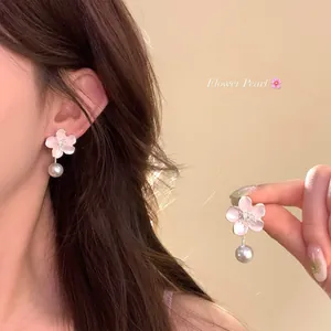 Elegant pink cherry blossom pearl earrings shown on model and detailed hand view.