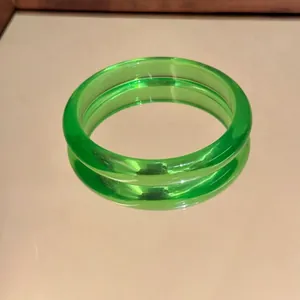 Primo piano di un bracciale rigido verde traslucido che si riflette su uno specchio