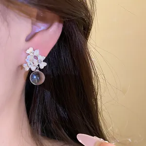 Détail de boucles d'oreilles fleurs d'été avec un pendentif en boule de verre claire