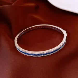 Close-up detail of a vintage palace style silver bangle with blue and clear cubic zircon stones.