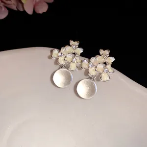 Gros plan détaillé de boucles d'oreilles fleurs en émail avec perles translucides brillantes