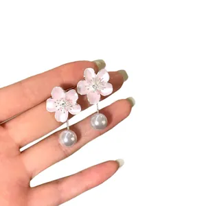 Elegant pink cherry blossom earrings with pearl tassels held in hand to show scale