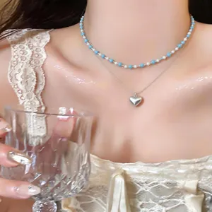 Close-up detail of a Korean style sweet heart pendant layered necklace on a model