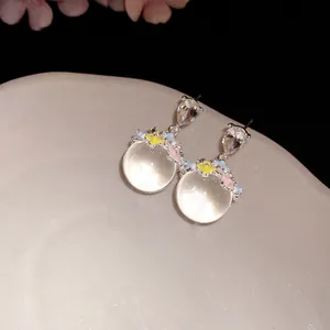 Gros plan de boucles d'oreilles fleurs avec pierres translucides et émail coloré.