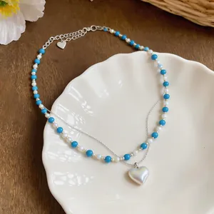 Detailed view of a blue and white beaded necklace with a heart pearl pendant.