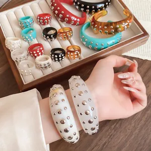 Detailed view of colorful resin rings and bangles decorated with silver metal rivets