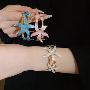Detailed view of vintage gold-tone metal open bangles featuring colorful enamel starfish