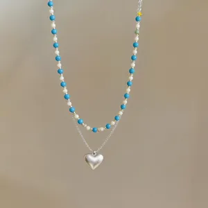 Detailed shot of double-layered necklace with blue beads and silver heart pendant