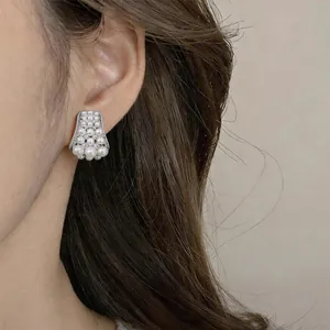 Primo piano di eleganti orecchini a lobo vintage con zirconi e perle indossati da una modella