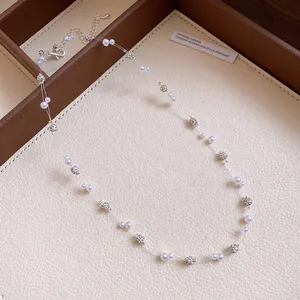 Detail shot of an elegant pearl and sparkling rhinestone necklace on transparent fishline