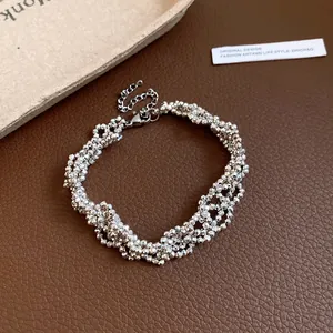 Detailed view of silver multi-strand faceted beaded necklace on leather background.