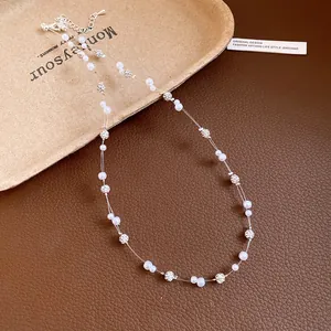 Close-up of elegant pearl and rhinestone beaded necklace on a textured background.