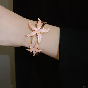 Macro detail view of pink enamel starfish on a gold-tone vintage open cuff bracelet