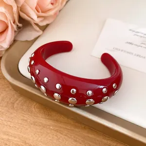 Macro view of a red resin cuff bracelet with silver studs on an elegant display tray
