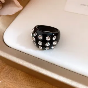 Detailed view of a stylish black resin ring inlaid with sparkling clear round rhinestones