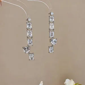 Detail shot of elegant long drop earrings featuring square and heart zircon stones