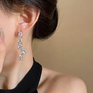 Detail view of a silver drop earring featuring square and heart-shaped zircon stones.