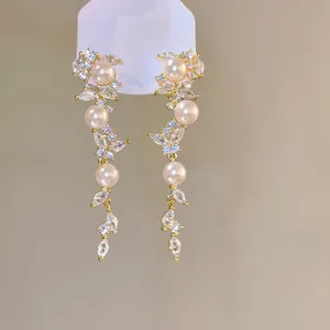 Detailed view of elegant gold-plated leaf tassel earrings with sparkly zircon and small pearls