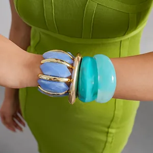 Macro detail of stacked blue and teal chunky acrylic geometric bracelets on a model's wrist